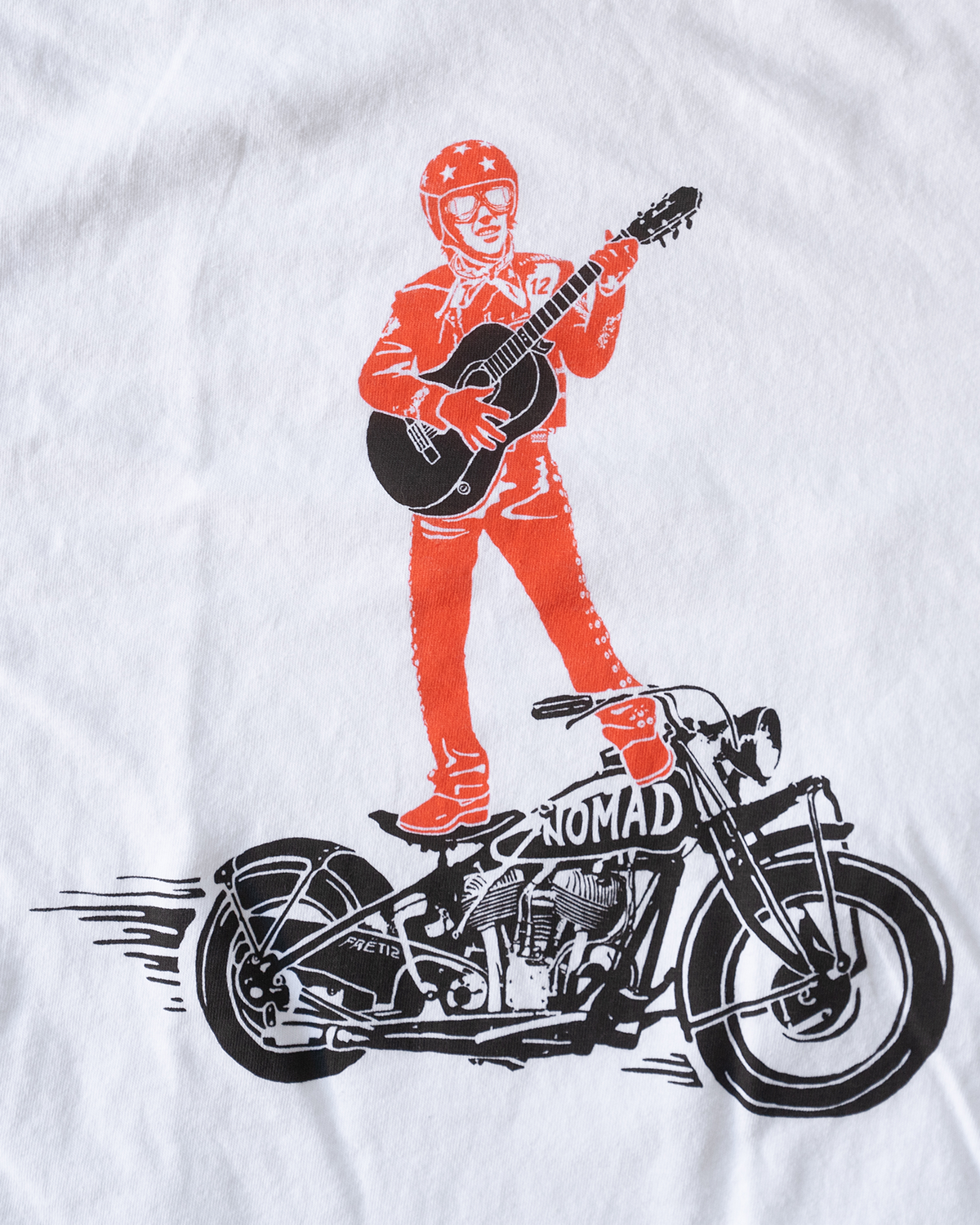 White FRET12 Mariachi Rider Tee showcasing a bold graphic of the legendary Mariachi Rider standing on a motorcycle, strumming a guitar, set against a clean, minimal backdrop.