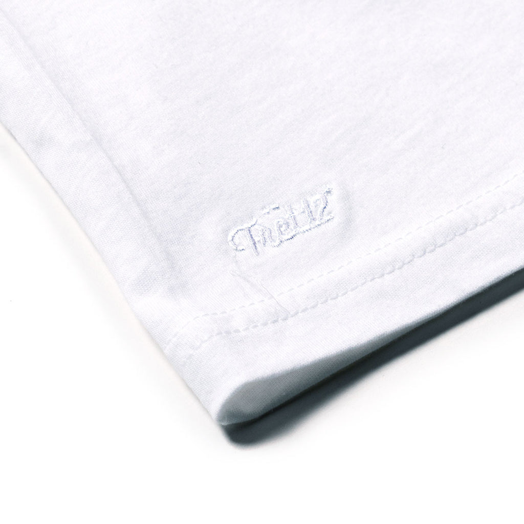 Closeup of white FRET12 embroidered logo on shirt hem